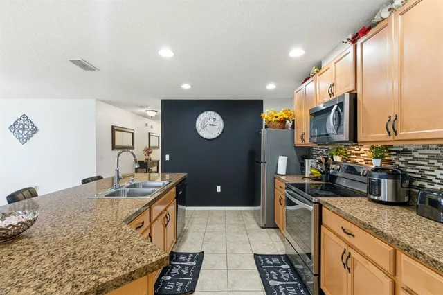 a kitchen with stainless steel appliances granite countertop a sink refrigerator and cabinets