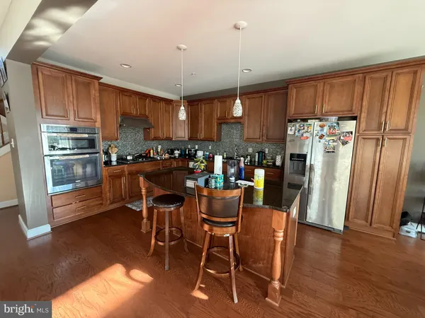 a kitchen with stainless steel appliances a dining table chairs refrigerator and sink