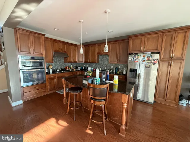 a kitchen with stainless steel appliances a dining table chairs refrigerator and sink