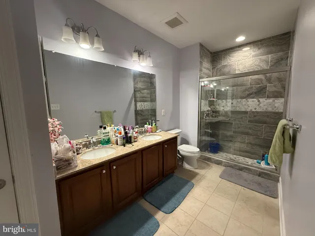 a bathroom with a double vanity sink mirror and shower