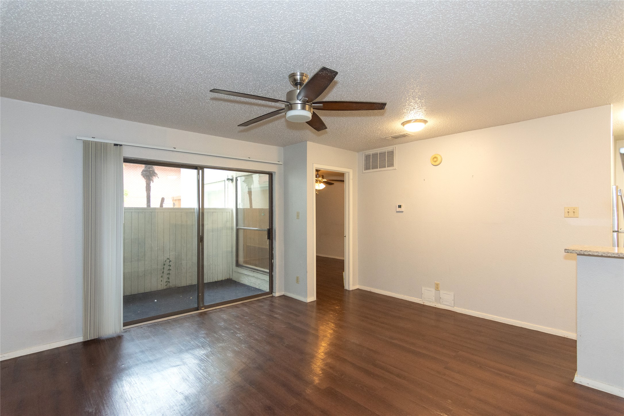 3115 Helms Street, Unit 106 Austin, TX 78705 - Photo 3 of 7 Rich hardwood-style flooring extends across this spacious living area, complemented by direct patio access through sliding glass doors.