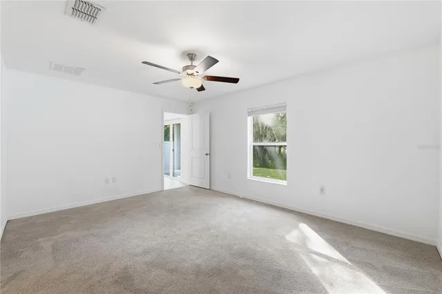 an empty room with a window and a fan
