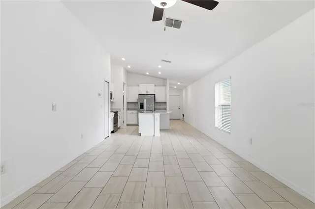 an empty room with windows and stainless steel appliances