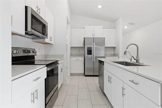 a kitchen with stainless steel appliances a sink dishwasher a refrigerator microwave and stove with wooden floor