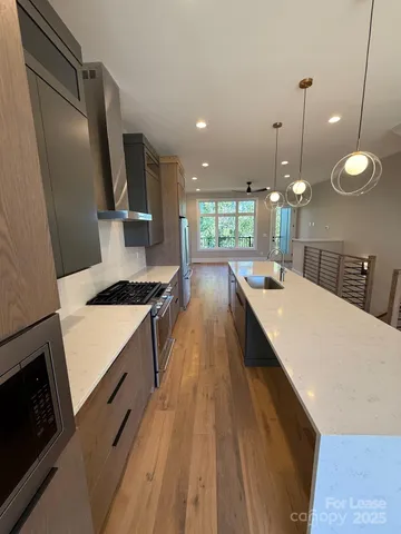 a large kitchen with kitchen island a stove a sink a refrigerator and a wooden floor