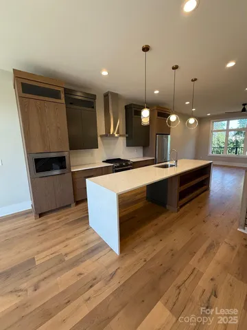 a large kitchen with stainless steel appliances kitchen island a large counter top and a wooden floor