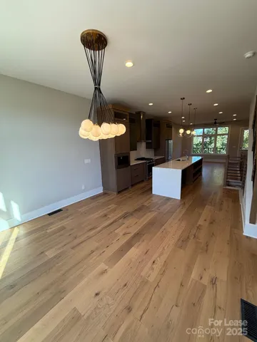 a view of a room with kitchen island stainless steel appliances wooden floor and living room view