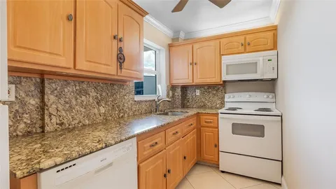 a kitchen with granite countertop white cabinets and white appliances