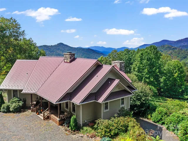 a front view of a house with a yard and mountain view in back