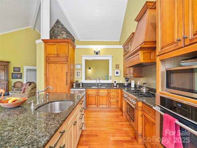 a kitchen with stainless steel appliances granite countertop a sink a stove and a wooden cabinets