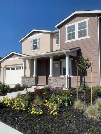a front view of a house with a garden and plants