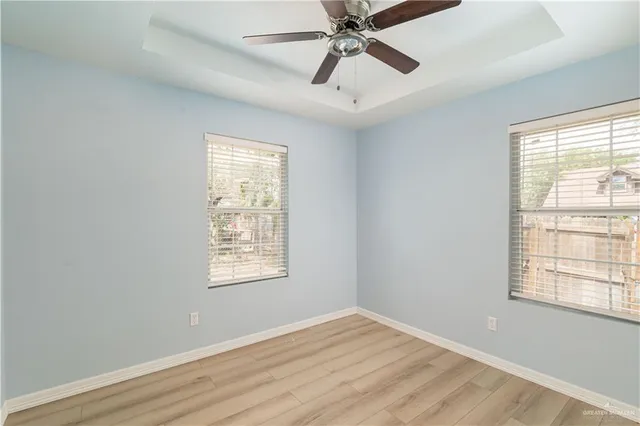 a view of an empty room with wooden floor and window