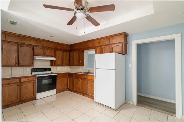 a kitchen with stainless steel appliances granite countertop a refrigerator a stove a sink a washer dryer and white cabinets