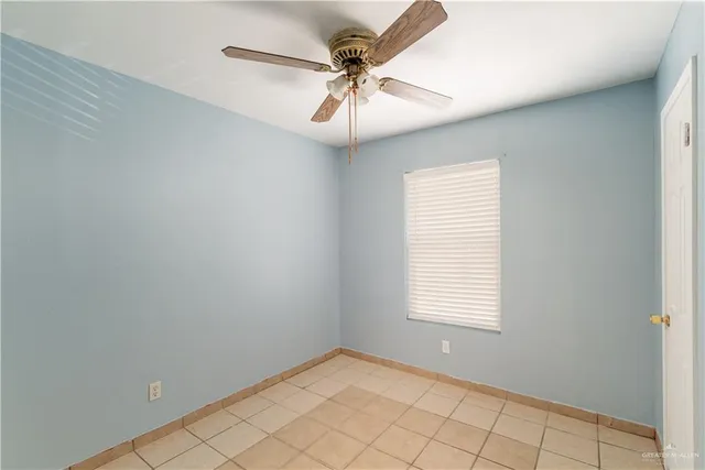 an empty room with a chandelier fan and windows