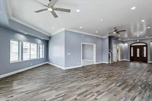 an empty room with windows and chandelier fan