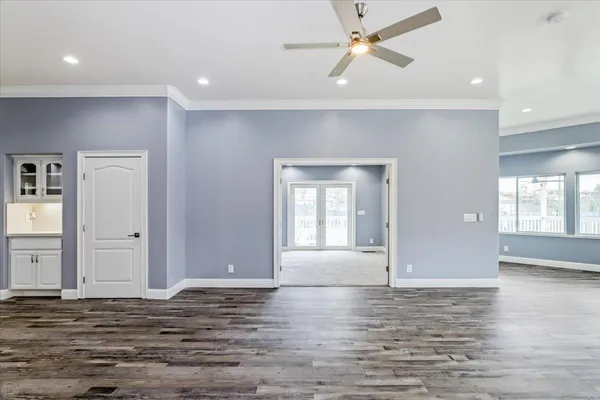 a view of an empty room with wooden floor and a window