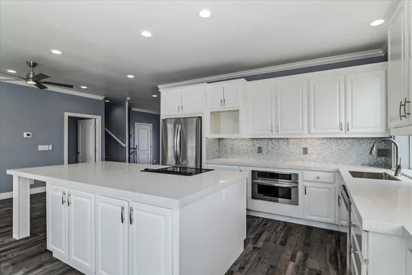 a large kitchen with stainless steel appliances a large counter top a stove and a refrigerator