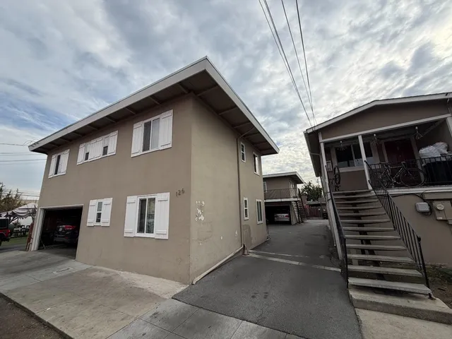 a backyard of a house with wooden fence and a bench