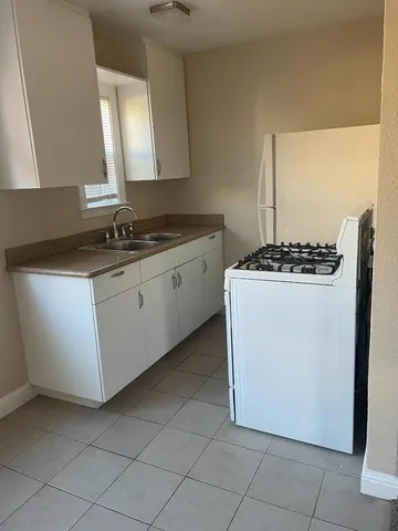 a kitchen with granite countertop white cabinets and white stove