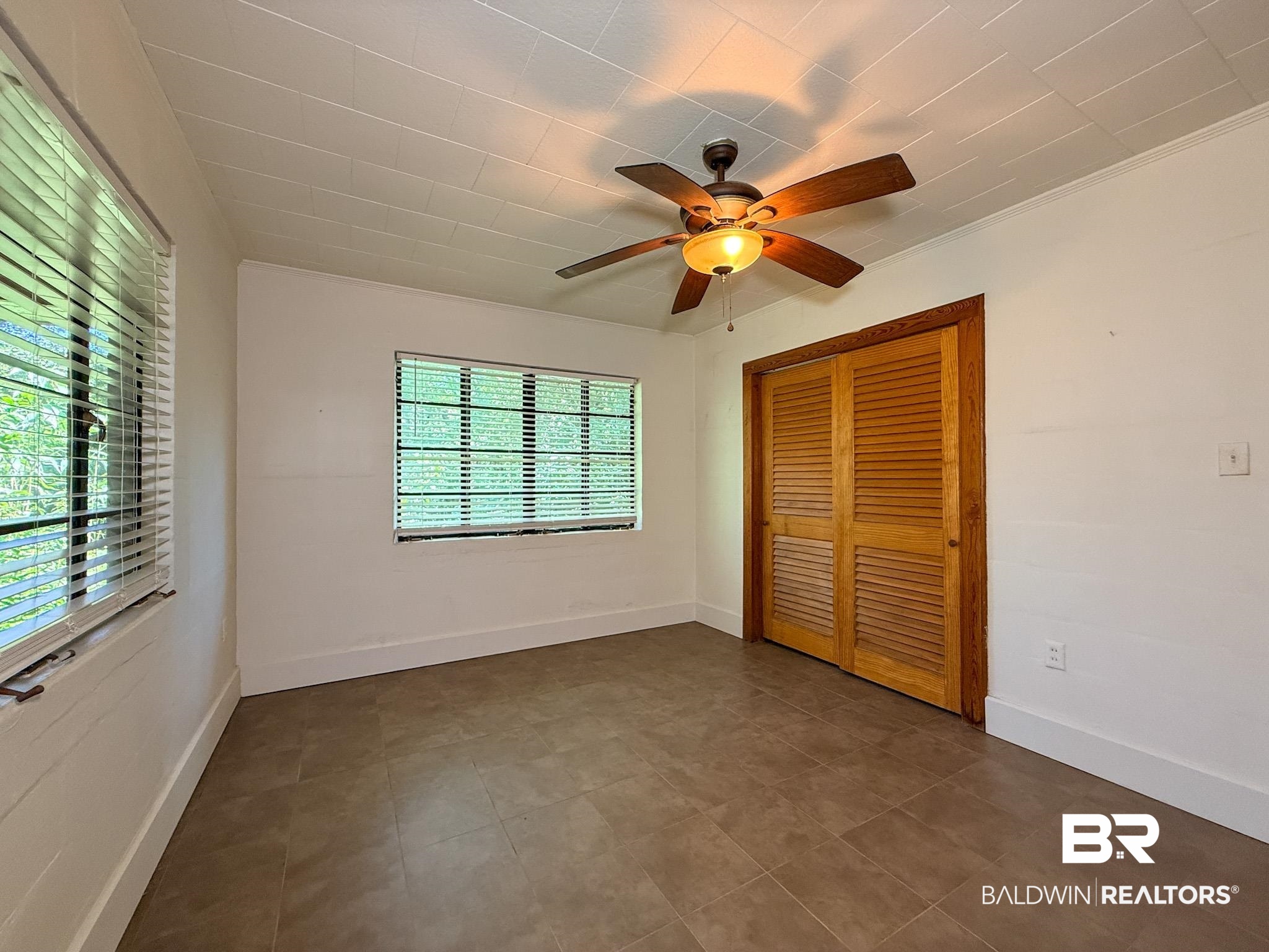 18711 Keller Road Foley, AL 36535 - Photo 23 of 38 Room featuring two windows with white blinds, a ceiling fan with light fixture, louvered bi-fold closet doors, and tile flooring