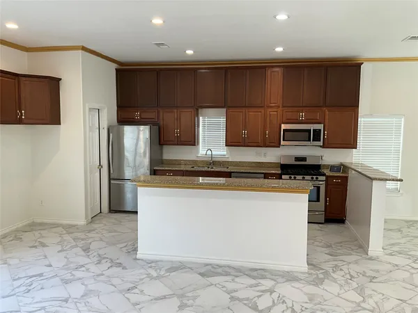 a kitchen with stainless steel appliances granite countertop a refrigerator a stove a sink and a microwave