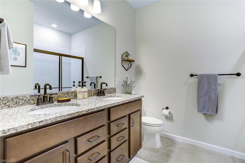 19809 Beechcrest Place Estero, FL 33928 - Photo 23 of 33 a bathroom with a granite countertop sink a toilet and a mirror
