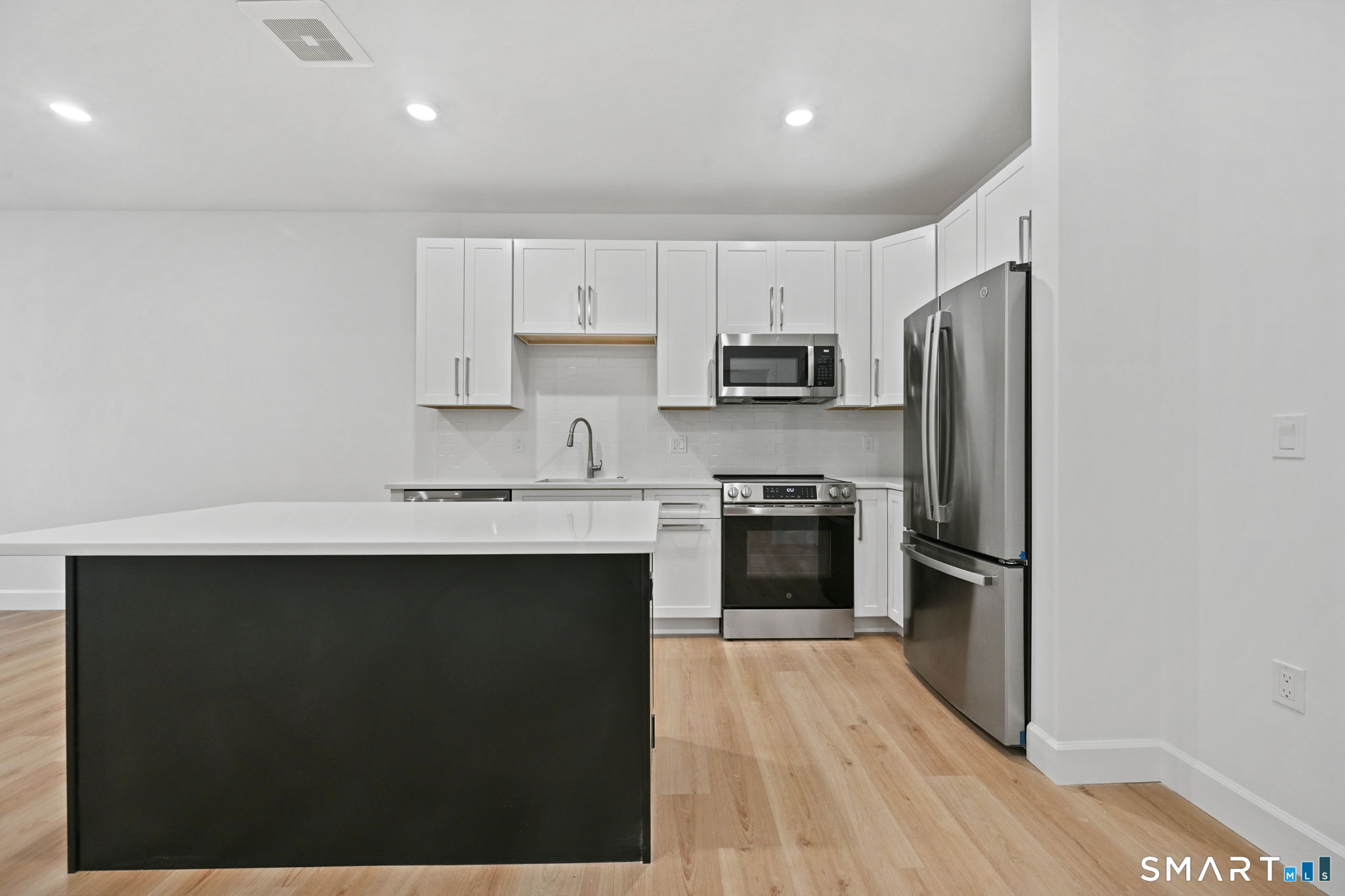 131 Beach Road, Unit 202 Fairfield, CT 06824 - Photo 11 of 32 a kitchen with kitchen island a sink stainless steel appliances and cabinets