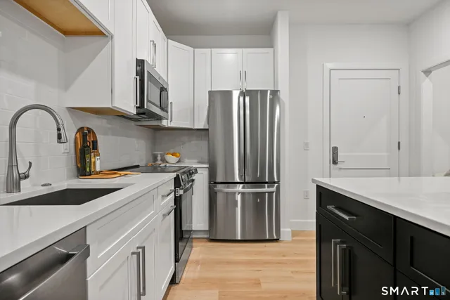 a kitchen with stainless steel appliances granite countertop a refrigerator sink and white cabinets