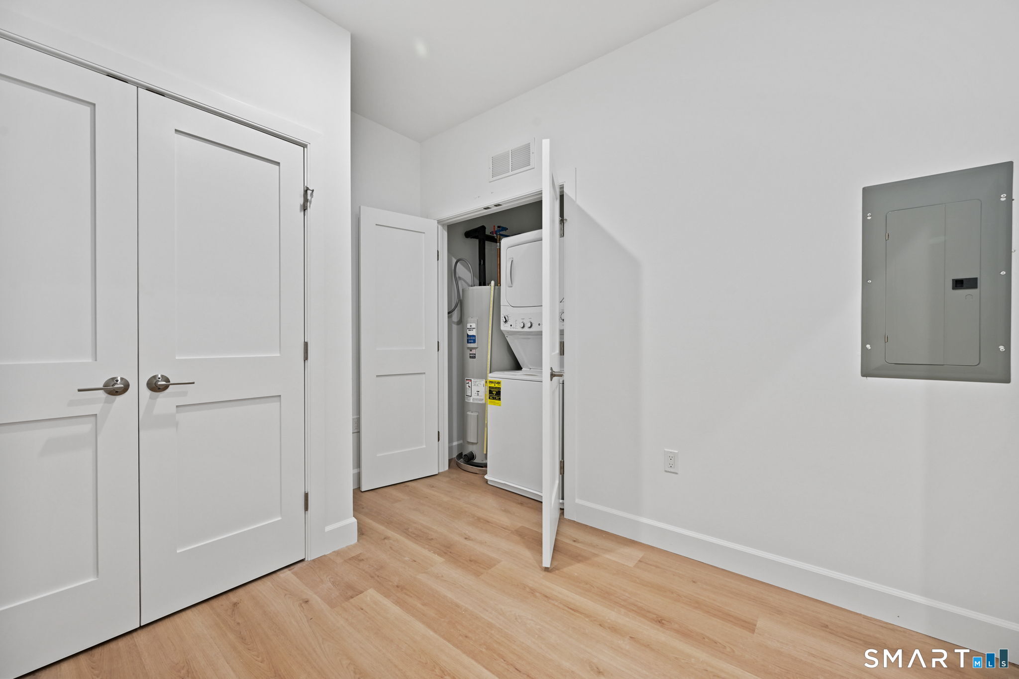 131 Beach Road, Unit 202 Fairfield, CT 06824 - Photo 23 of 32 a view of an empty room with wooden floor and a hallway