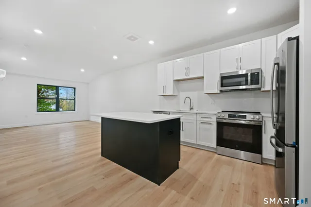 a kitchen with stainless steel appliances granite countertop a stove a sink and a microwave