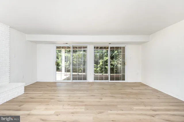 a view of an empty room with wooden floor and a fireplace