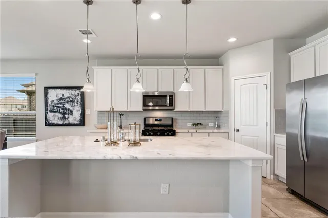 a kitchen with kitchen island a counter space a sink cabinets stainless steel appliances and a center island
