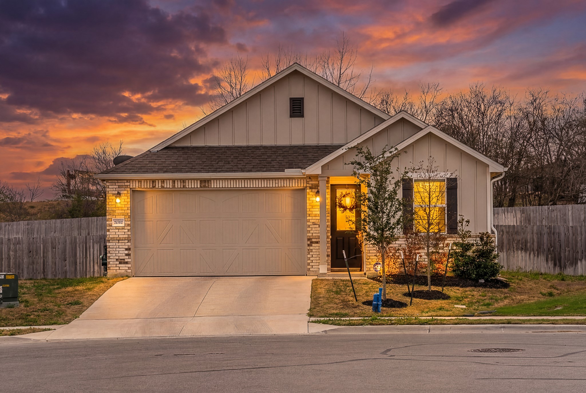 View of front of house with board and batten siding, an attached garage, brick siding, concrete driveway, and a shingled roof