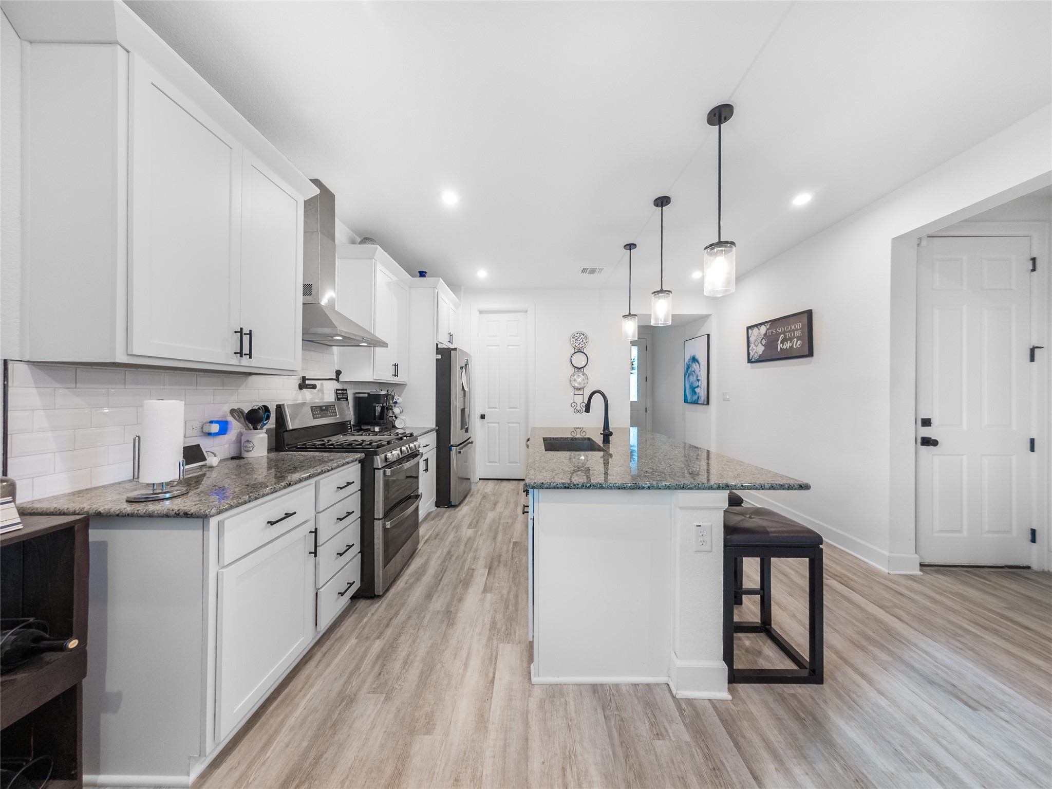 20811 Phebe Foster Street Manor, TX 78653 - Photo 9 of 40 Kitchen featuring stainless steel appliances, dark stone counters, white cabinets, light wood-style floors, and a breakfast bar