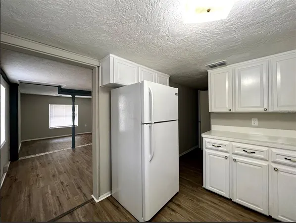 a kitchen with a refrigerator a stove top oven and cabinets