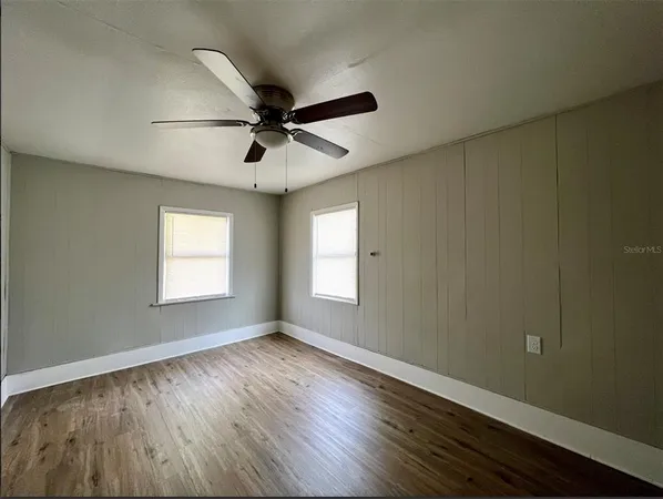 a view of empty room with wooden floor and fan