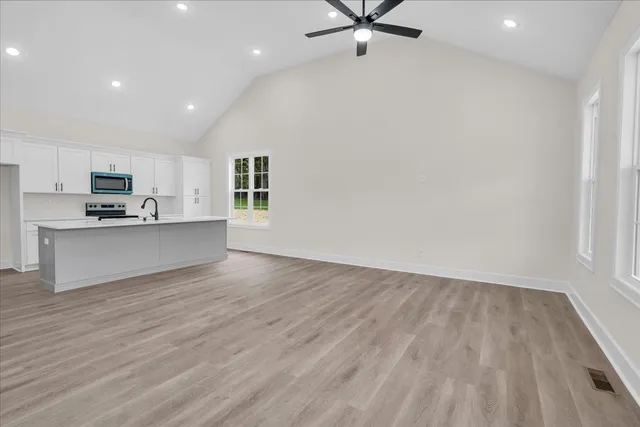 a view of kitchen and empty room with wooden floor