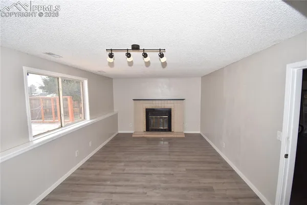 a view of an empty room with a window and fireplace
