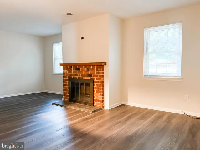 an empty room with wooden floor fireplace and windows