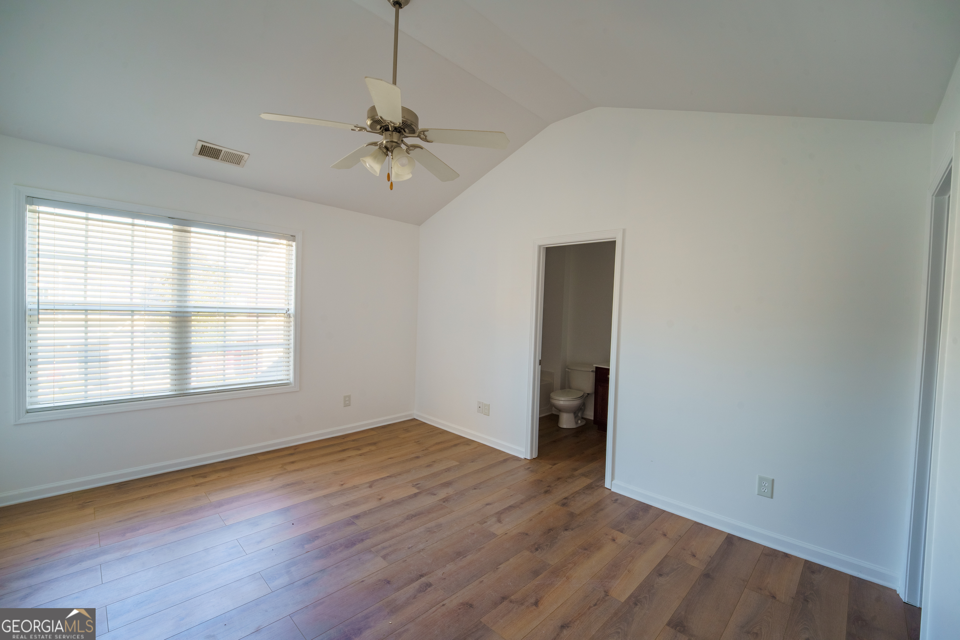 2555 Flat Shoals Road, Unit 1402 South Fulton, GA 30349 - Photo 9 of 18 an empty room with wooden floor chandelier fan and windows