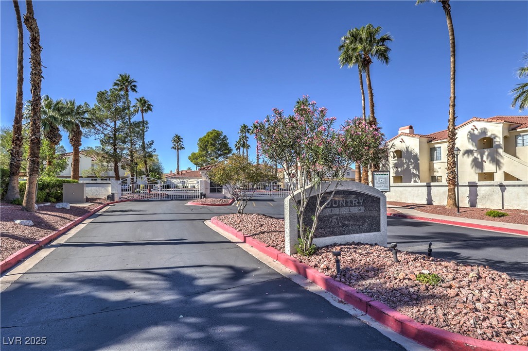 View of asphalt street featuring curbs, a gate, a gated entry, and a residential view