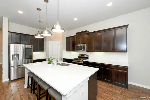 a kitchen with stainless steel appliances a kitchen island a stove a refrigerator a sink and a cabinets