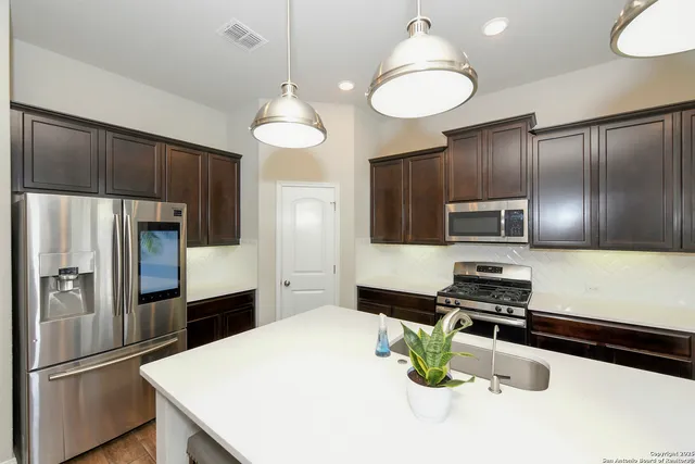 a kitchen with sink a refrigerator and chairs