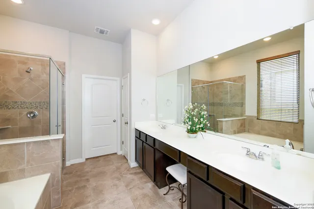 a bathroom with a double vanity sink mirror and shower