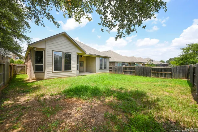 a backyard of a house with plants and large tree
