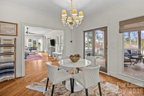 a dining room with wooden floor a chandelier a wooden table and chairs