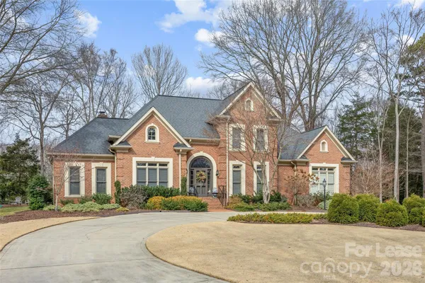 a view of a brick house next to a yard with large trees
