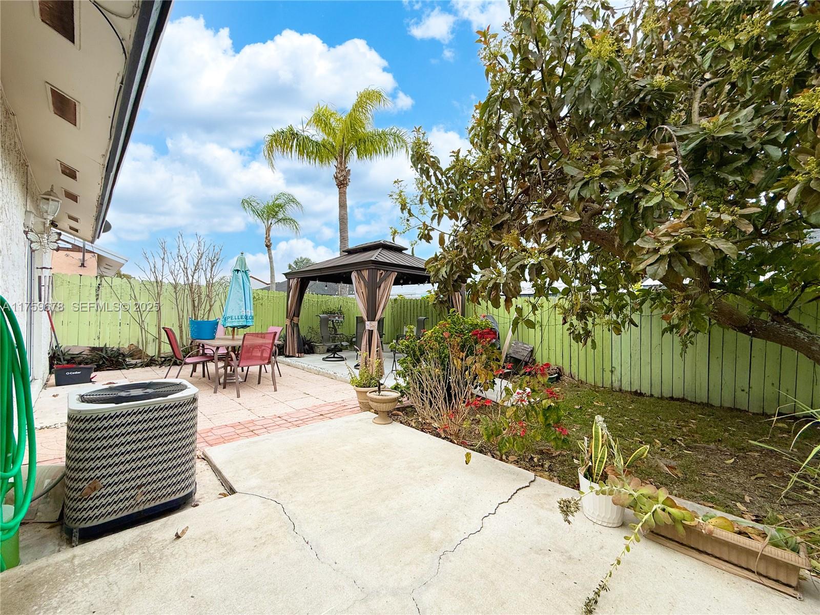 20520 Southwest 124th Place Miami, FL 33177 - Photo 27 of 34 a view of a patio with table and chairs potted plants and large tree