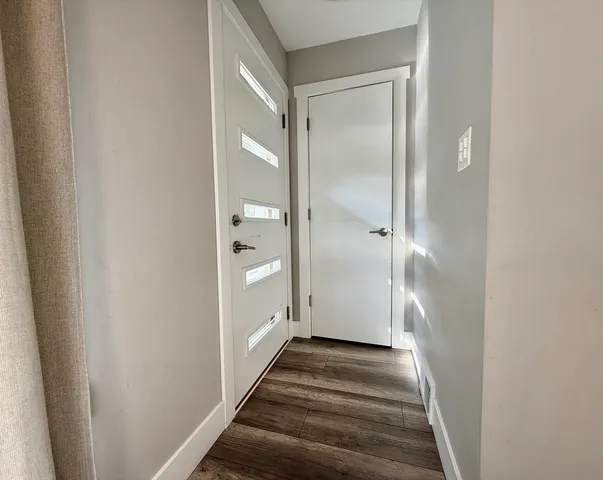 a view of a hallway with wooden floor and a bathroom