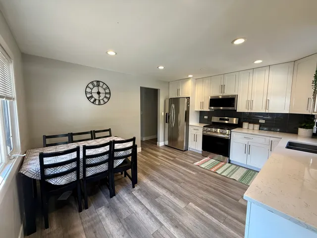 a kitchen with stainless steel appliances kitchen island granite countertop a stove a sink and a refrigerator with wooden floor